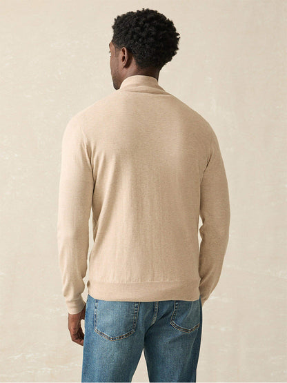 A person wearing the Faherty Brand Movement Quarter Zip in Soft Dune Heather and blue jeans stands facing away against a light background, enjoying enhanced comfort from the COOLMAX blend.