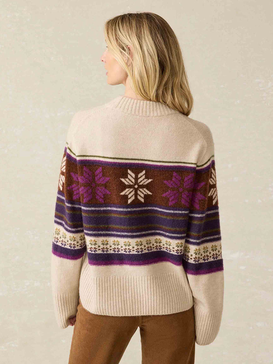 A person wearing the Faherty Brand Snowdrift Sweater in Multi Snowflake stands with their back facing you.