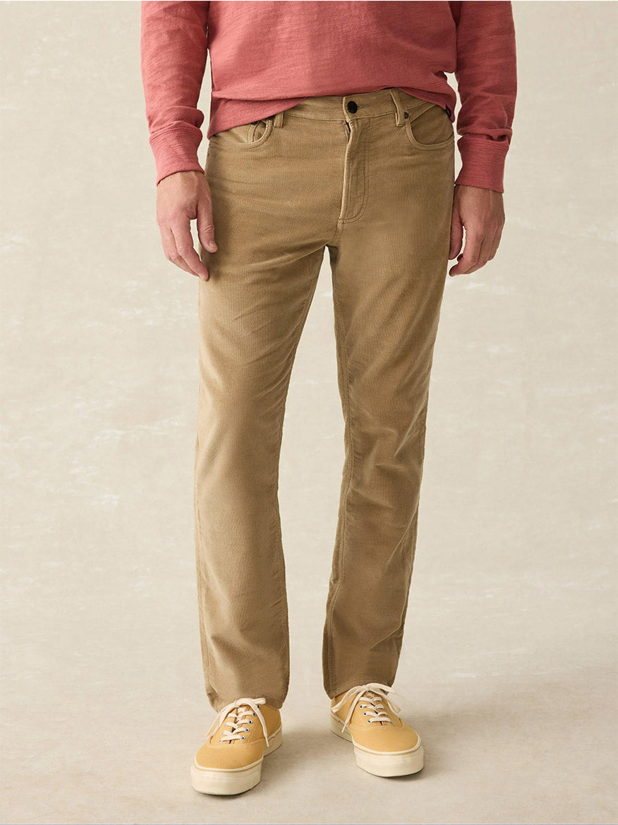 A person dressed in a red long-sleeve shirt, Faherty Brand Stretch Terry 5-Pocket Pants in Barley with a classic fit, and yellow sneakers.