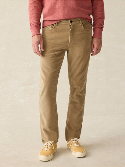 A person dressed in a red long-sleeve shirt, Faherty Brand Stretch Terry 5-Pocket Pants in Barley with a classic fit, and yellow sneakers.