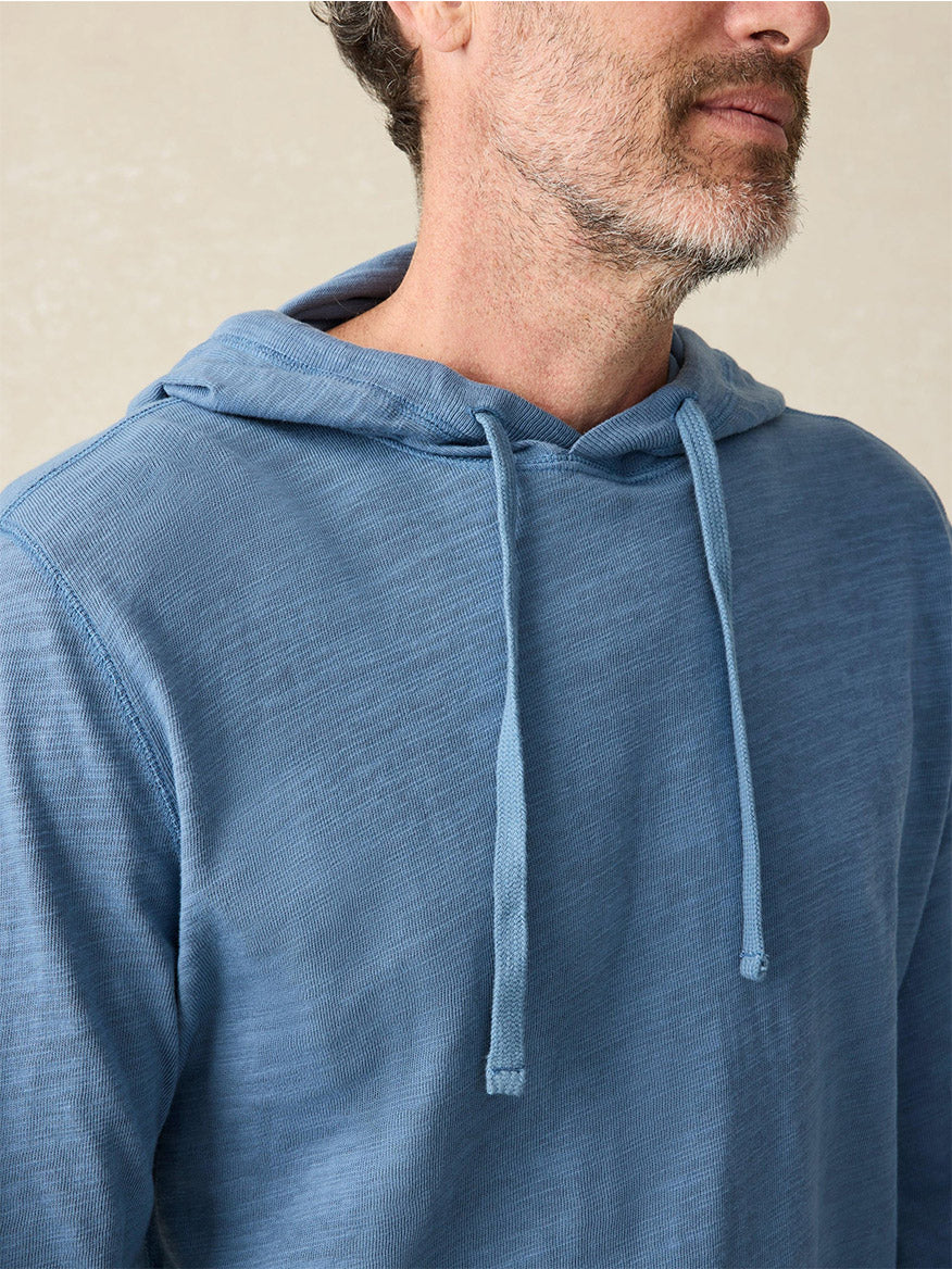 A person wearing the Faherty Brand Sunwashed Slub Hoodie in Aqua Ocean, made from American-grown cotton, is shown from the shoulders up against a neutral background, highlighting its relaxed fit.