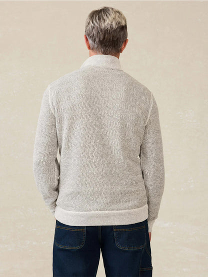 A person with short gray hair, wearing the Faherty Brand Whitewater Quarter Zip in Grey Shell Loop and dark blue jeans, stands with their back to the camera against a plain background.
