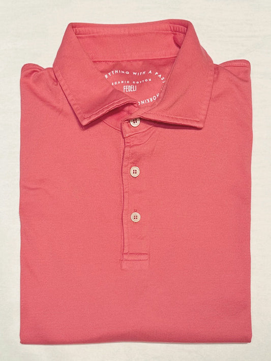 The Fedeli Zero Organic Cotton Short Sleeve Polo in Watermelon, featuring a collar and elegant mother of pearl buttons, is folded and displayed on a light-colored surface.