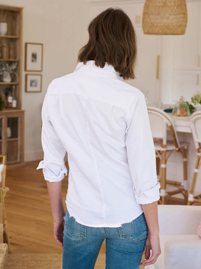 Woman standing in a room, viewed from behind, wearing a Frank & Eileen Barry Tailored Button-Up Shirt in White Tattered Denim and blue jeans.