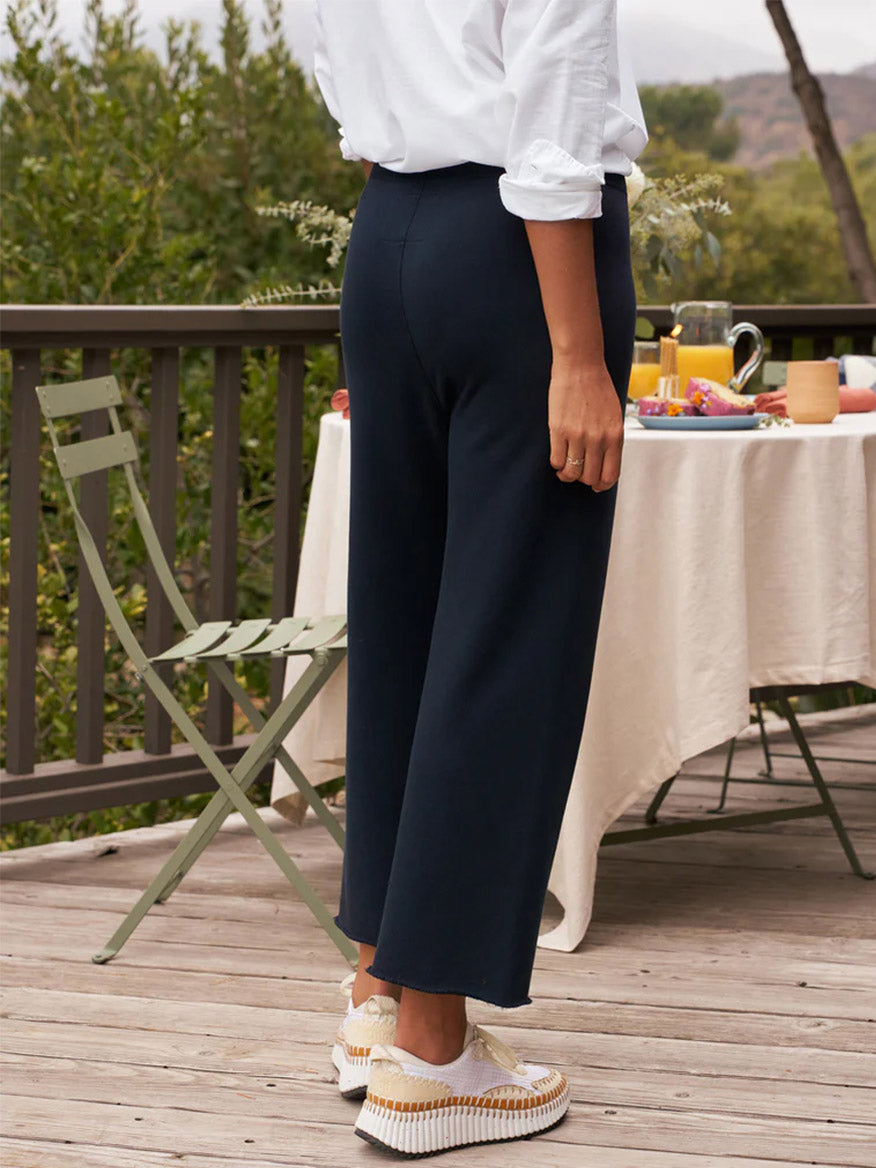 A person standing on a deck wearing Frank & Eileen Catherine Favorite Sweatpant in British Royal Navy Triple Fleece and white platform shoes, with a breakfast table set in the background.