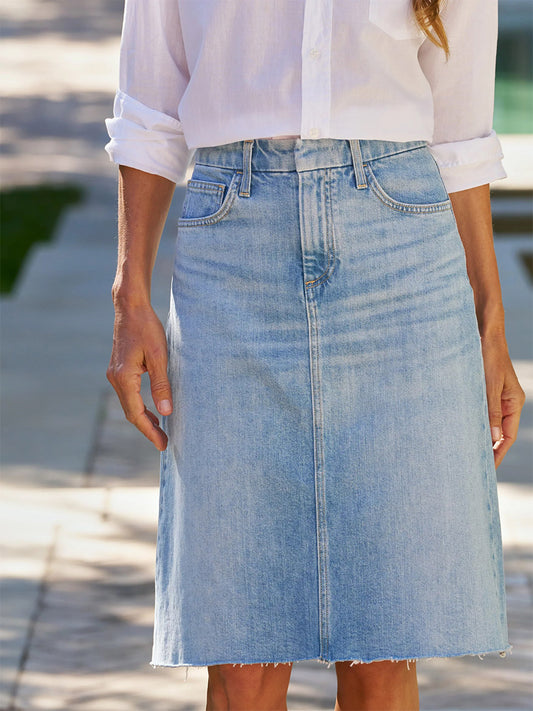 A person wears a white button-up shirt with rolled sleeves and the Frank & Eileen Donny Denim Midi Skirt in Classic Wash while standing outdoors.