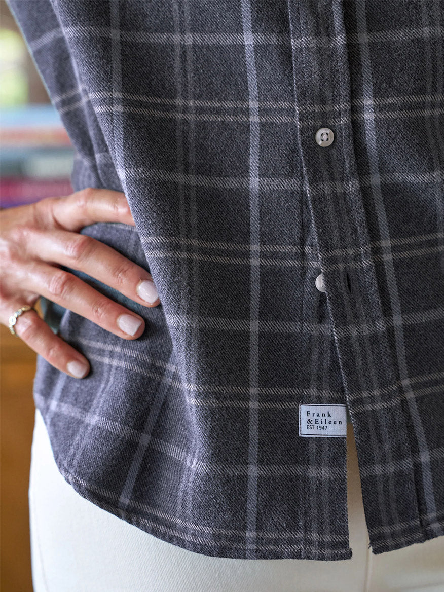 A person wears the Frank & Eileen Eileen Relaxed Button-Up Shirt in Charcoal & Blue Plaid, featuring bust-flattering buttons. Their hand, with white nail polish and a gold ring, rests on their hip, embodying an effortless California vibe.