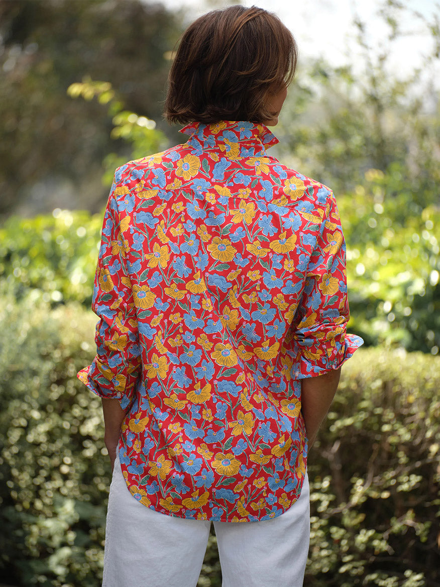 A person stands outdoors with their back to the camera, wearing the Frank & Eileen Eileen Relaxed Button-Up Shirt in Red Flowers and white pants, embodying casual California style.