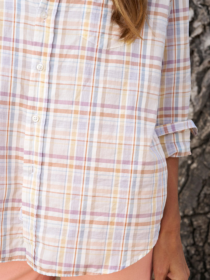 Close-up of a person wearing the Frank & Eileen Eileen Relaxed Button-Up Shirt in Sand & Purple Plaid, with the sleeves rolled up to highlight its relaxed fit. The backdrop features a textured surface, likely a tree trunk, enhancing the casual California vibe.