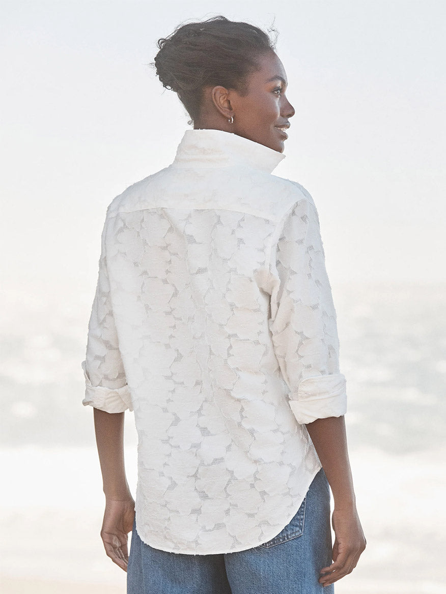 A person wearing the Frank & Eileen Eileen Relaxed Button-Up Shirt in Textured White Flowers with blue jeans, embodying casual California style outdoors while facing away from the camera.