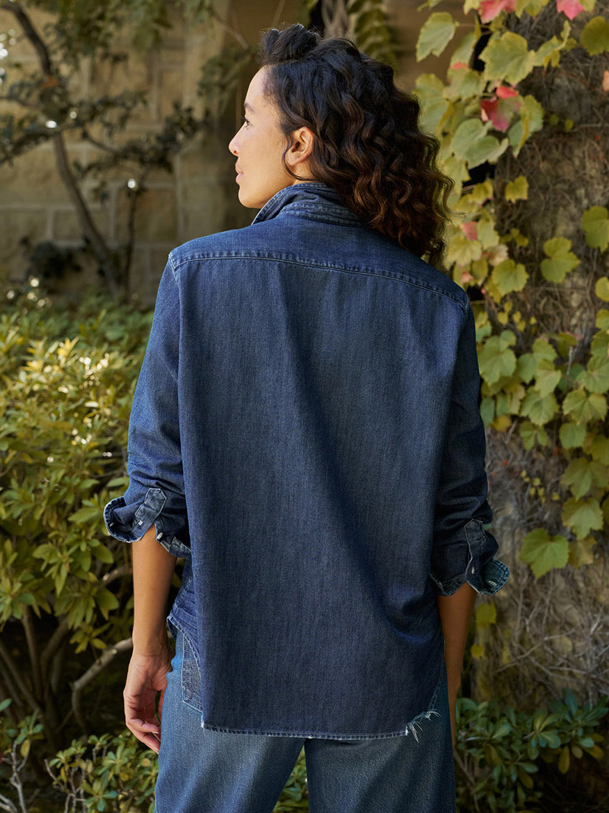 A person viewed from the back wearing a Frank & Eileen Eileen Relaxed Button-Up Shirt in Vintage Dark Indigo Wash, styled with rolled sleeves for a casual California look.