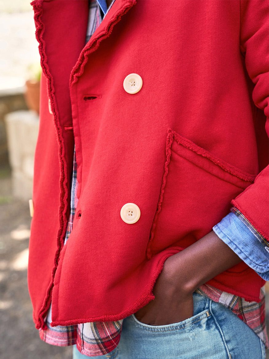 A person wearing the Frank & Eileen Mini Belfast Crop Peacoat in Crimson Triple Fleece over a blue plaid shirt and jeans stands outdoors with one hand in a pocket.