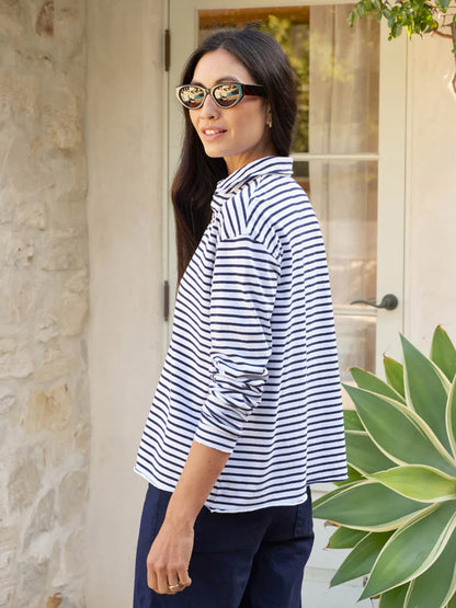 Woman wearing Frank & Eileen Patrick Popover Henley in White/British Royal Navy Stripe Heritage Jersey shirt and sunglasses standing near a plant outside a building.