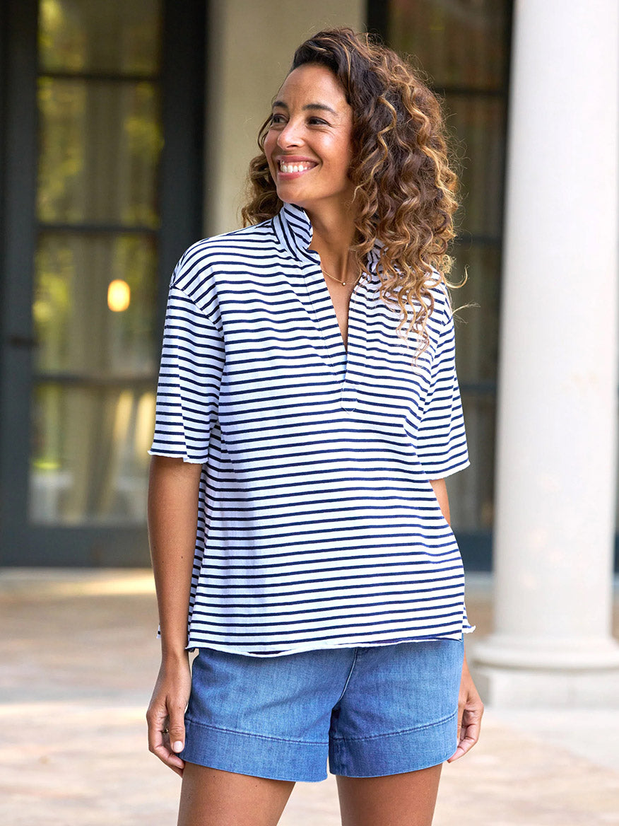 Smiling outside by a building, a person wears the Frank & Eileen Perry NYC Crewneck Tee in Navy French Stripe with denim shorts, embodying effortless New Yorker style.