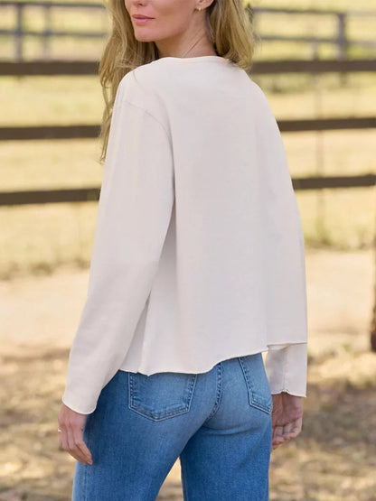 A person seen from behind, wearing a Frank & Eileen Quinn Long-Sleeve Crewneck Tee in Vintage White Heritage Jersey, featuring a relaxed fit, raw-edge hem, and blue jeans.