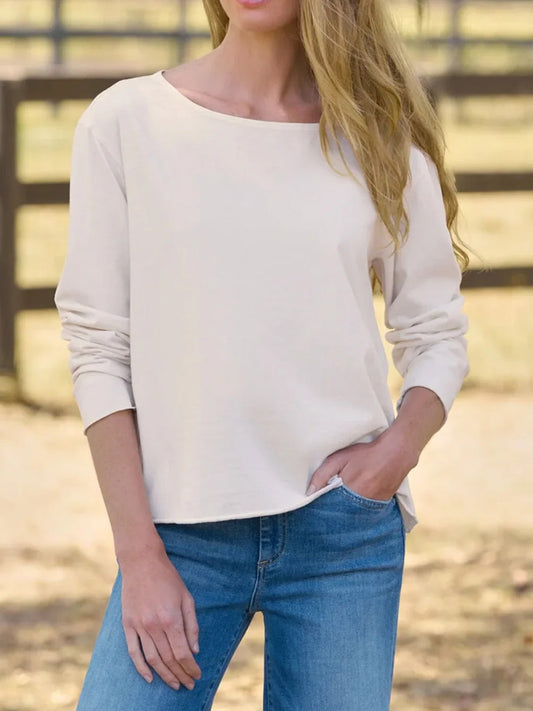 A woman wearing a Frank & Eileen Quinn Long-Sleeve Crewneck Tee in Vintage White Heritage Jersey with a relaxed fit and raw hem paired with blue jeans.