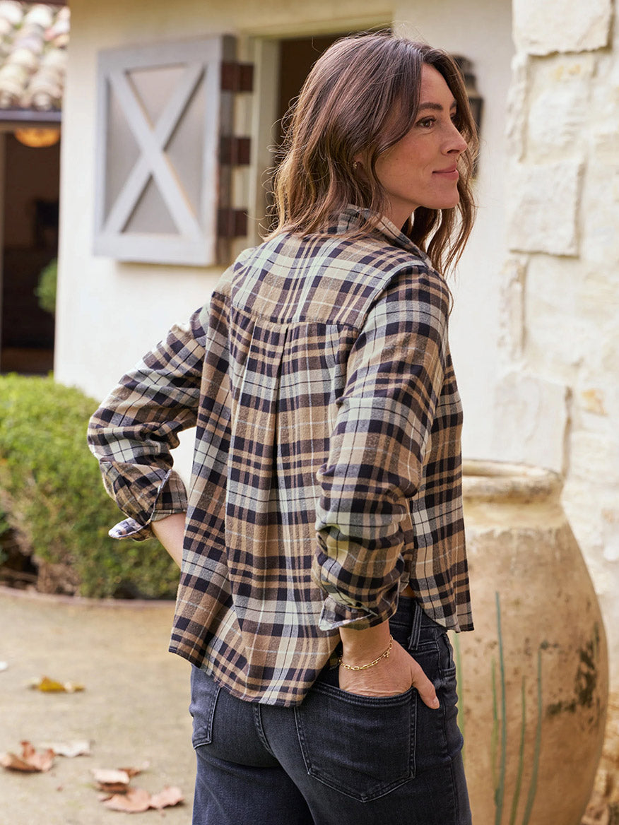 A person standing outdoors in front of a building, wearing the Frank & Eileen Silvio Untuckable Button-Up Shirt in Sand & Camel with Black Plaid and jeans, with one hand in their pocket, exuding Italian tailoring vibes through subtle fashion-forward detailing.