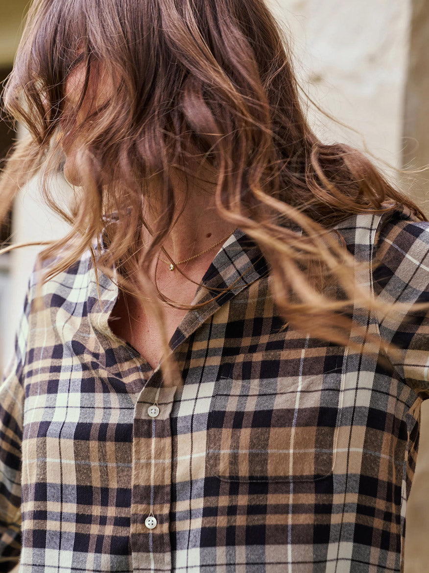 A person with wavy hair is wearing a Frank & Eileen Silvio Untuckable Button-Up Shirt in Sand & Camel With Black Plaid, turning their head to the side.