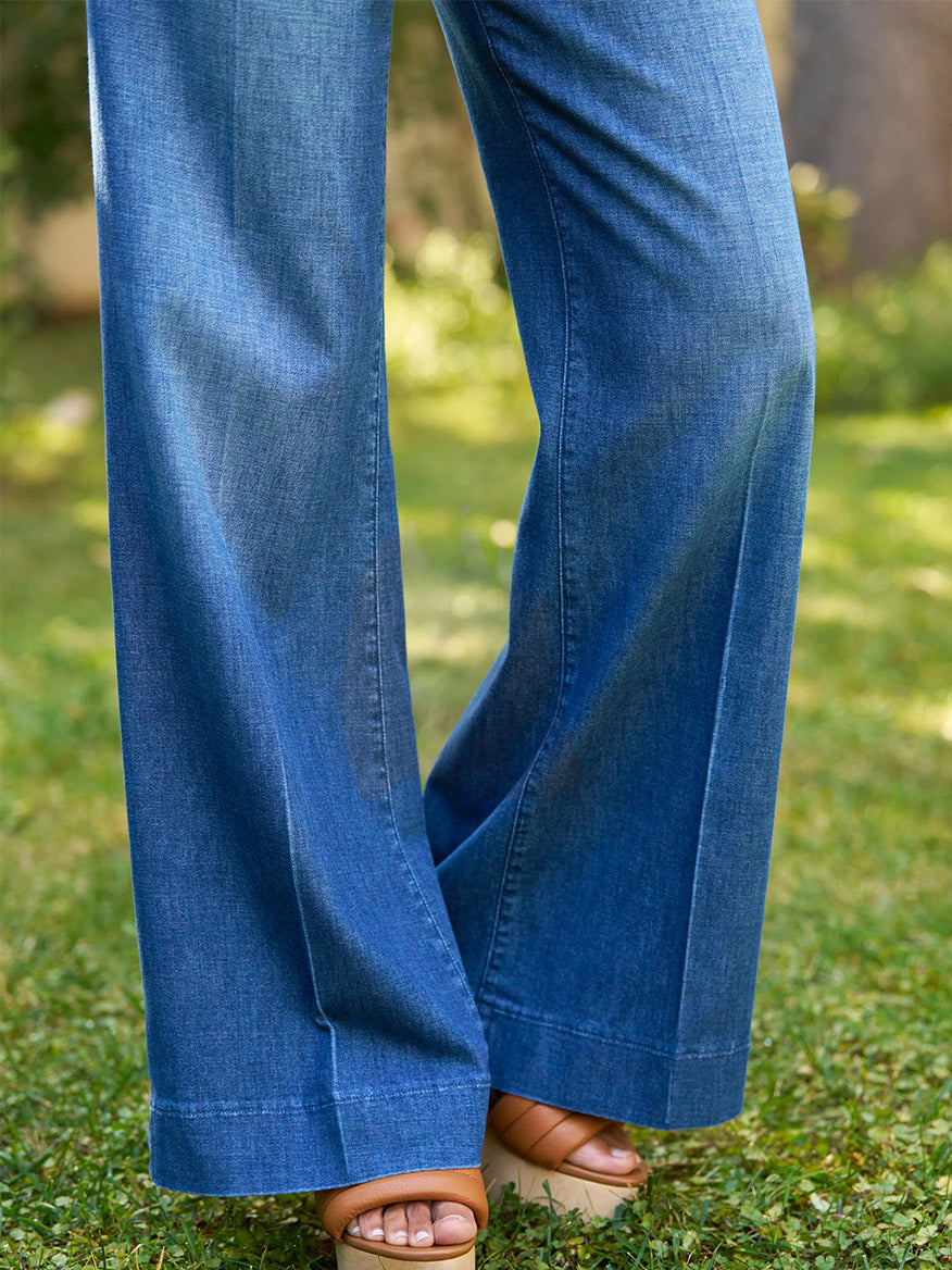A person in Frank & Eileen West Village NYC Wide-Leg Trouser in 1984 Wash with tan heeled sandals stands outdoors on green grass.