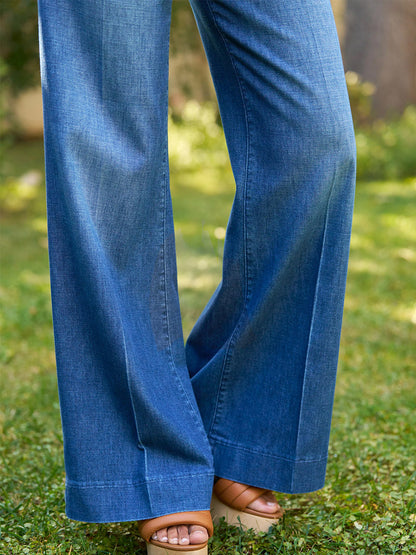 A person in Frank & Eileen West Village NYC Wide-Leg Trouser in 1984 Wash with tan heeled sandals stands outdoors on green grass.