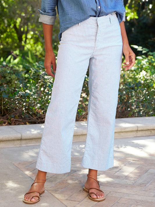 Person standing outdoors in Frank & Eileen Wexford Wide-Leg Linen Pant in Blue and White Stripe, paired with a blue long-sleeve shirt with rolled-up sleeves and brown sandals.