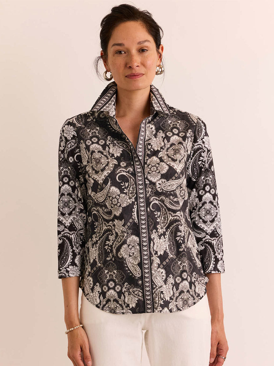 A woman poses against a plain background, wearing the Hinson Wu Lizette 3/4 Sleeve Top in Black Paisley and white pants.