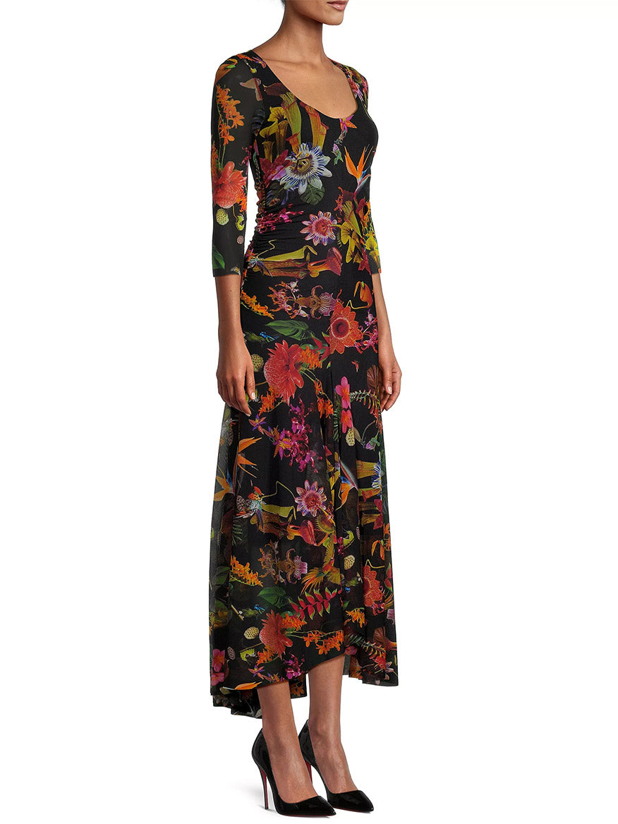 Sentence with product name: A person standing side-on wearing a Fuzzi Abito Floral Maxi Dress in Nero Multi, designed in Italy, and black heels.