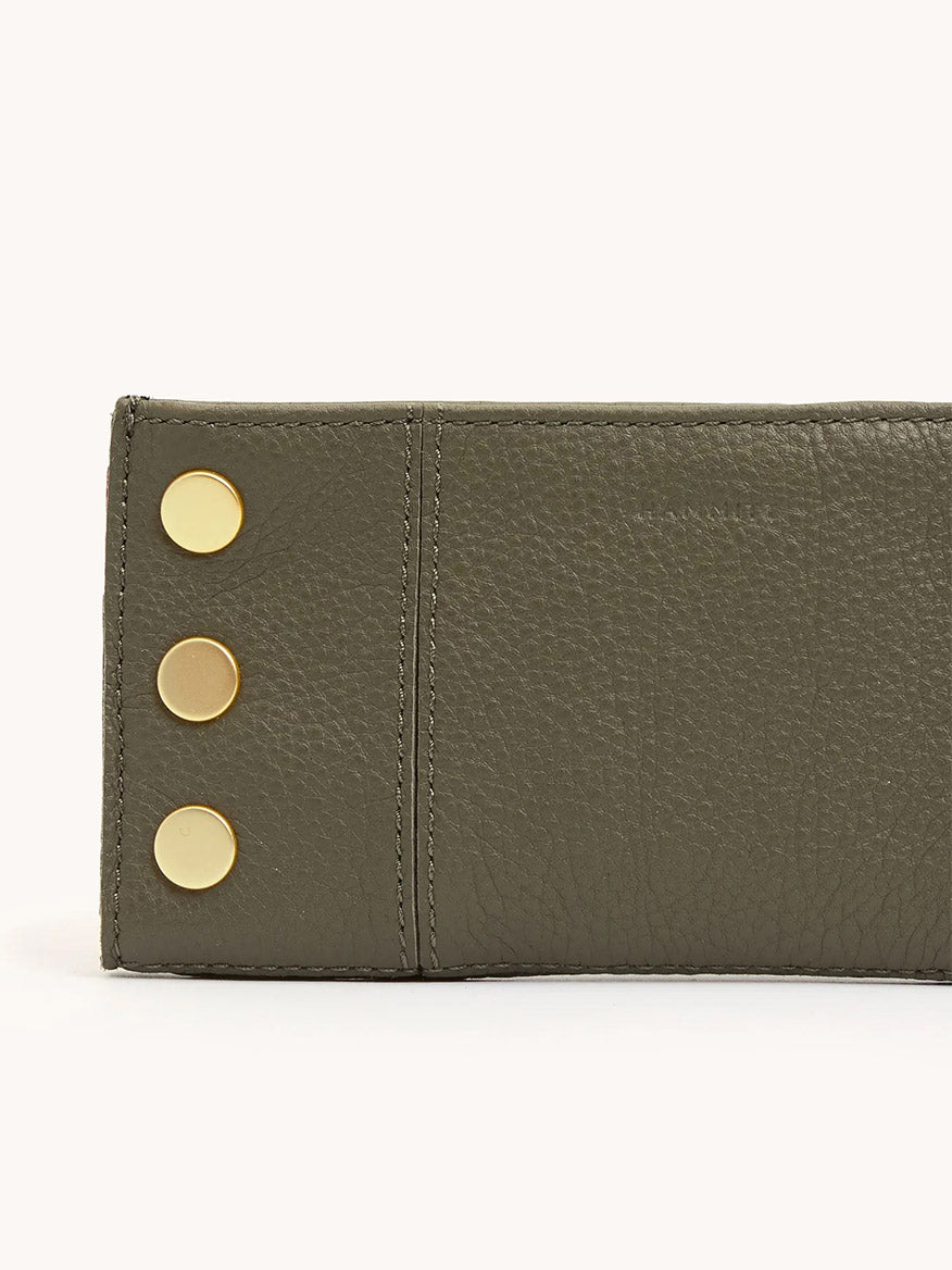 A close-up of the Hammitt Los Angeles 110 North Wallet in Olive/Brushed Gold, featuring green pebble leather and three gold circular studs along the left edge.
