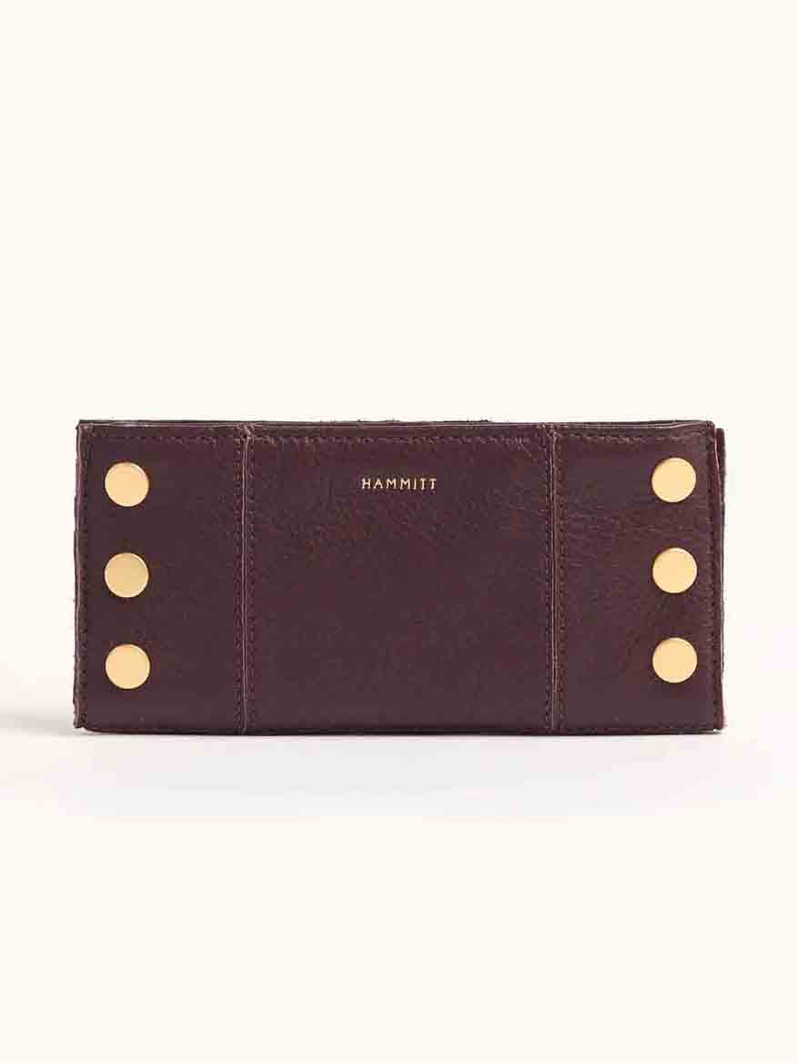 A folding wallet in a deep Cabernet Pebble shade, featuring gold button accents and the word "HAMMITT" embossed on its brown leather surface.