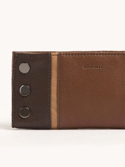 Close-up of the Hammitt Los Angeles 110 North Wallet in Orchestra Brown, made from pebbled leather with three metal button accents on the left and "HAMMIE" embossed on the right.