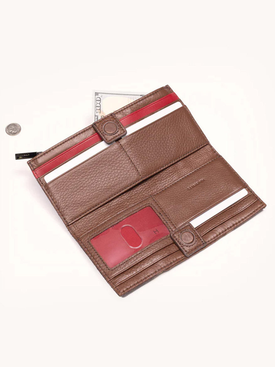 The Hammitt Los Angeles 110 North Wallet in Orchestra Brown, made from pebbled leather, showcases multiple slots with a visible credit card and a partially exposed hundred-dollar bill. A coin is placed next to it on a pristine white background.