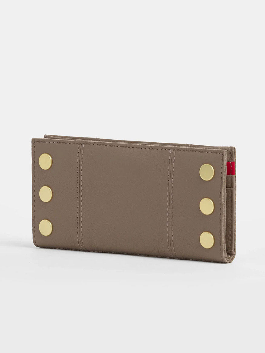 The Hammitt Los Angeles 110 North Wallet in Sculpted Taupe, featuring a pebbled leather finish and gold button accents on both sides with ample credit card slots, rests elegantly on a white surface.