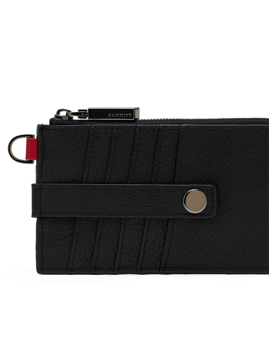 The Hammitt Los Angeles 210 East Wallet in Black/Gunmetal features pebbled black leather, a snap button strap, diagonal stitch details, a zipper closure, and a small metal ring on the left side—combining timeless style and functionality for the perfect sleek card holder.