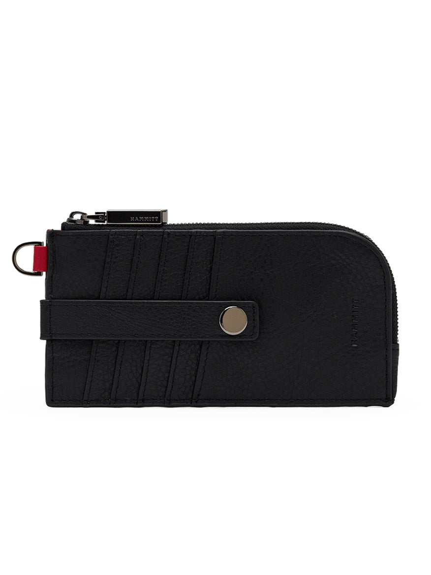 The Hammitt Los Angeles 210 East Wallet in Black/Gunmetal features a rectangular silhouette crafted from black pebbled leather, complete with card slots, a snap-button strap, and a secure zipper closure. A distinctive red fabric tab near the zipper pull adds a signature touch of style to this sleek wallet.