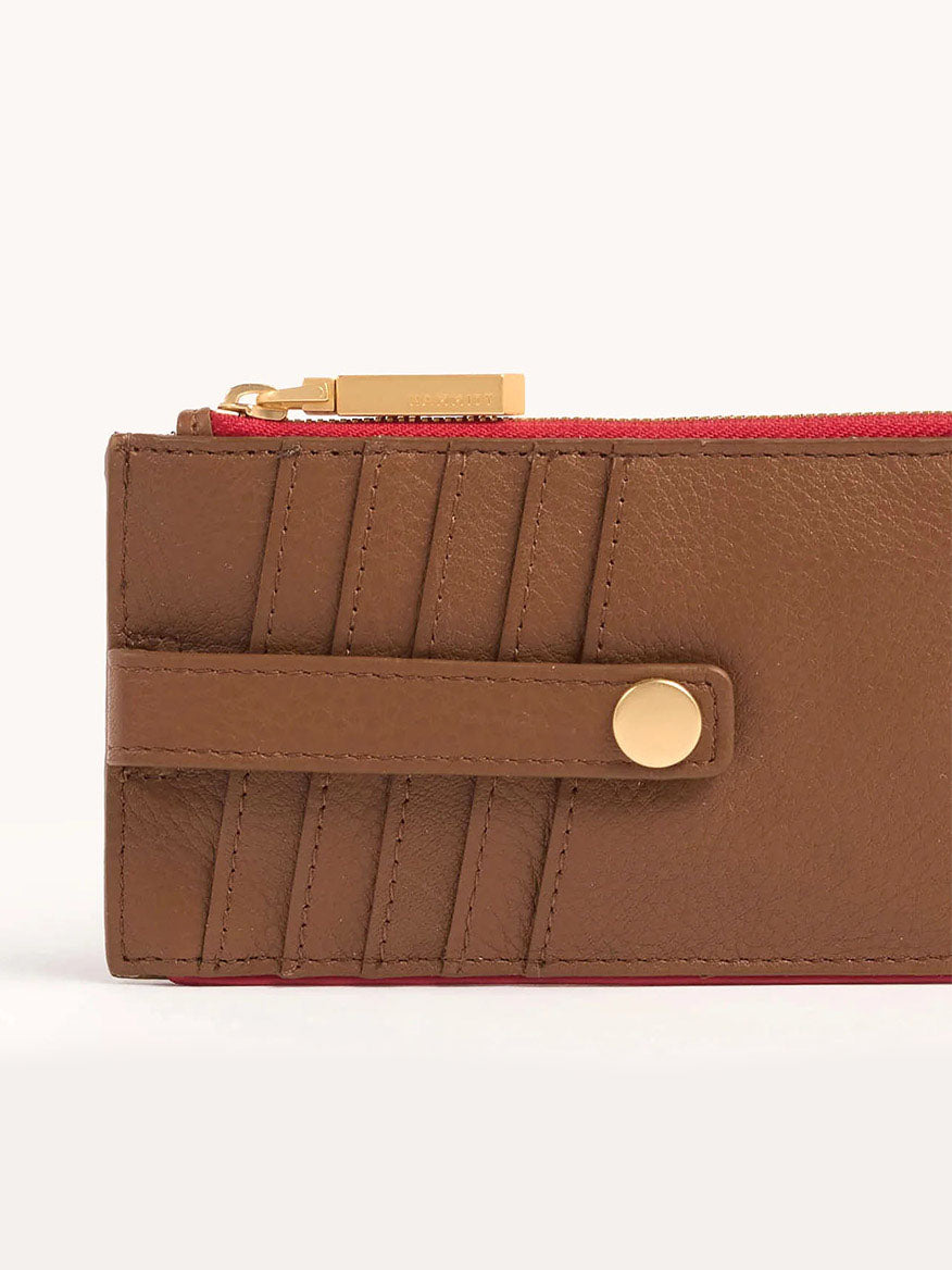 The Hammitt Los Angeles 210 West Wallet in Mahogany Pebble is made from soft pebbled leather, featuring a gold zipper and brushed gold hardware. The rich red inner lining enhances the elegance of this stylish accessory.