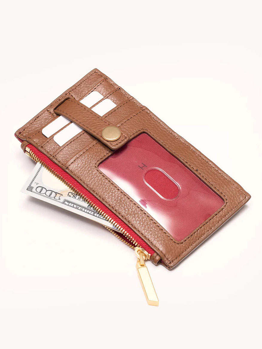 The Hammitt Los Angeles 210 West Wallet in Mahogany Pebble is a brown snap wallet featuring soft pebbled leather, card slots, a transparent ID window, and brushed gold hardware for elegance. It's partially open to reveal a red card and U.S. currency inside.