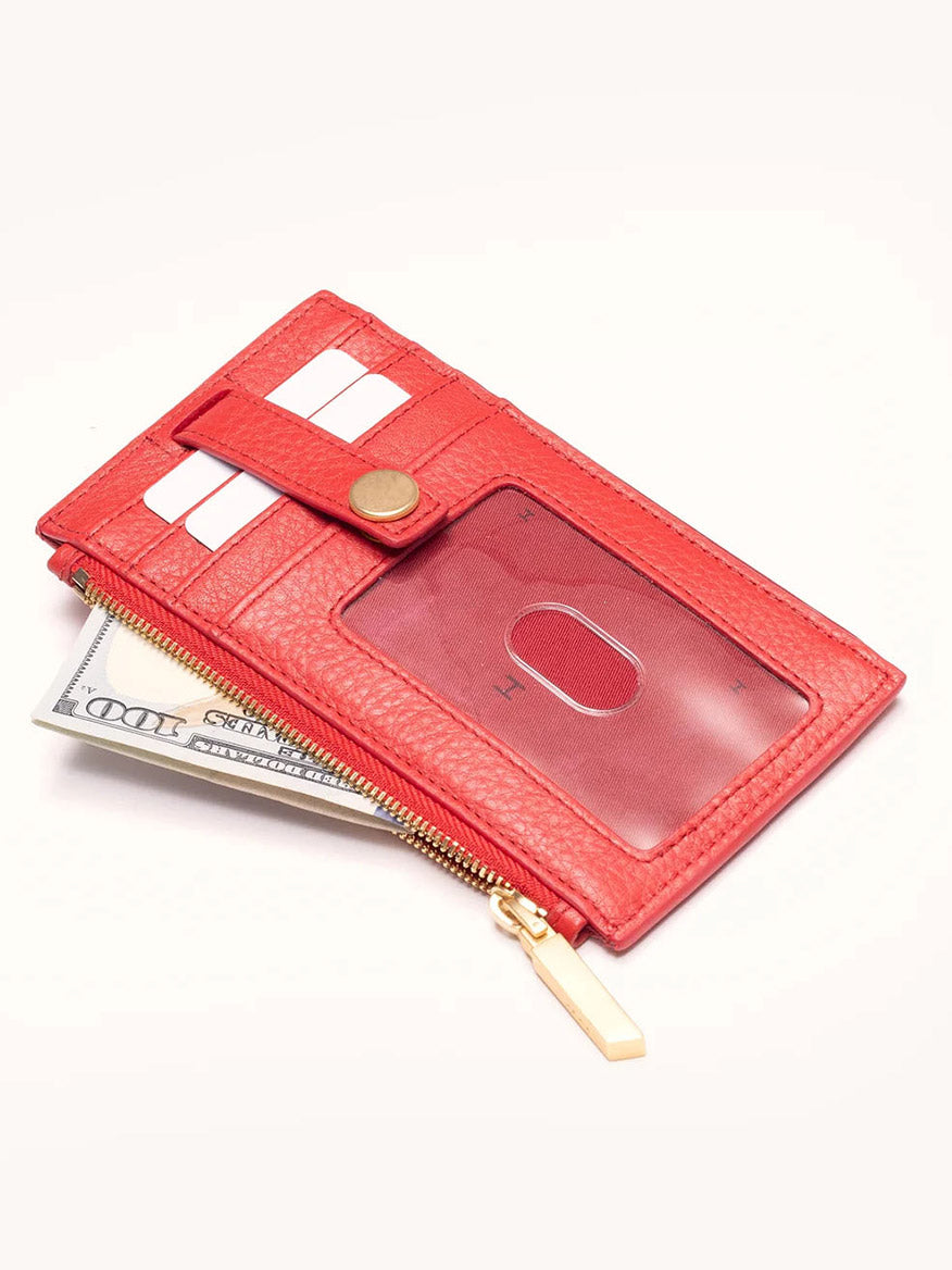 The Hammitt Los Angeles 210 West Wallet in Poppy Red is made of pebbled leather and includes card slots, a transparent ID window, a zipper pocket, and shows a $100 bill partially visible.