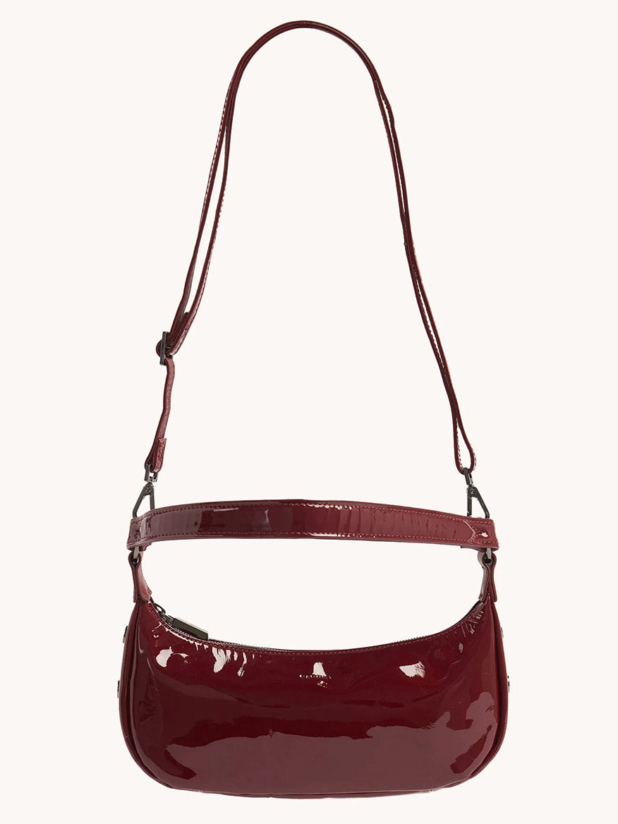 The Hammitt Los Angeles Becker Small in Pirouette Patent is a glossy handbag in a striking burgundy red hue, crafted from Italian patent leather, featuring metal hardware and a short strap.