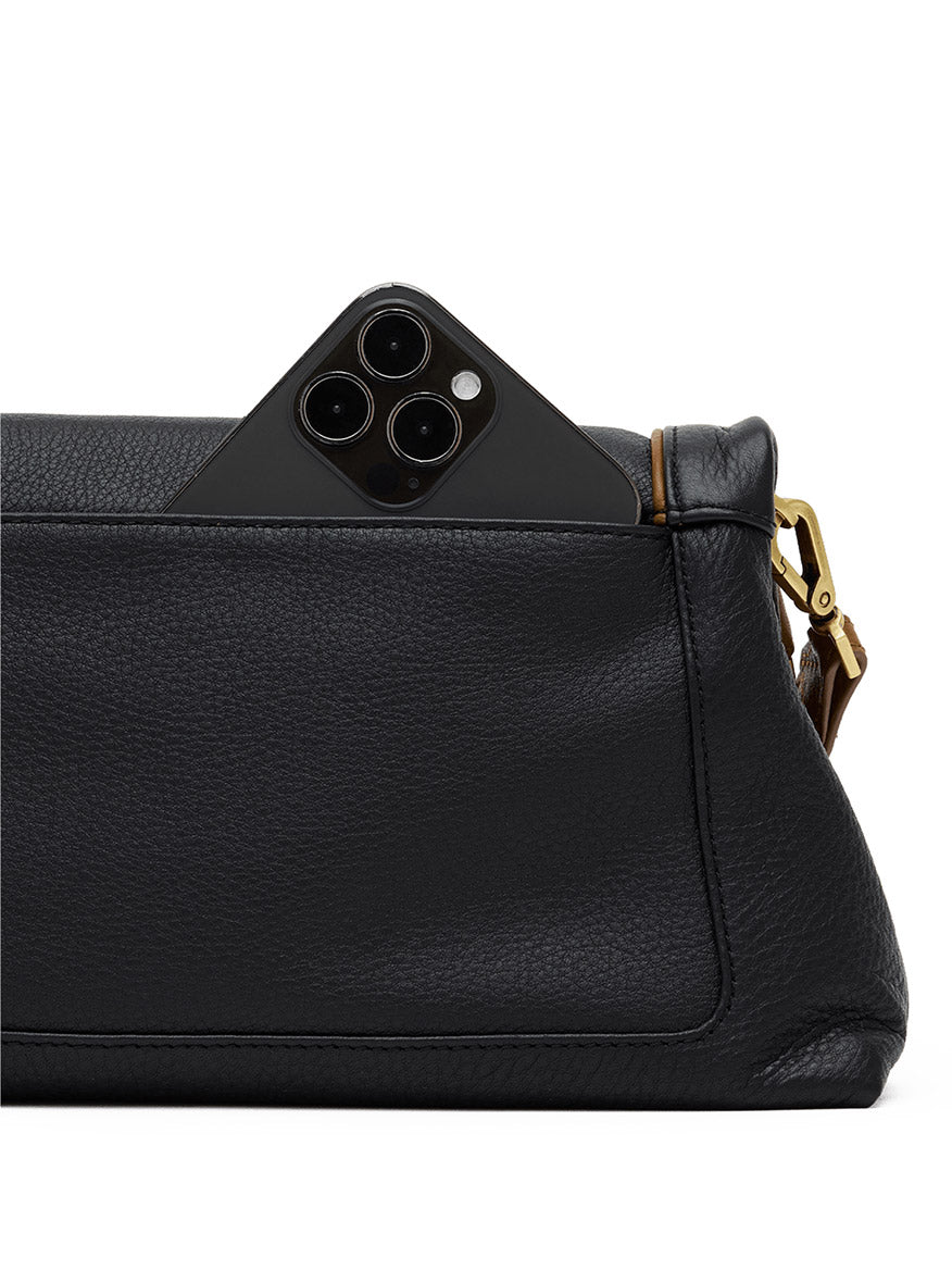 A black smartphone is partially visible in the outer pocket of a Hammitt Los Angeles Beverly Medium bag in East End/Antique Gold, featuring pebbled black leather, gold-tone hardware, and a sleek crossbody strap.