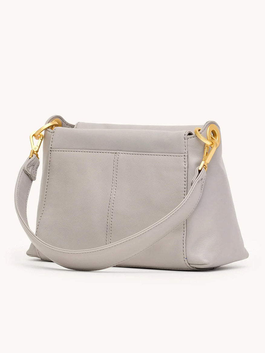The Hammitt Los Angeles Bryant Medium Crossbody Bag in Stormy/Brushed Gold features a light gray finish, wide strap, gold-tone hardware, visible stitching, and two exterior slip pockets shown from the back.