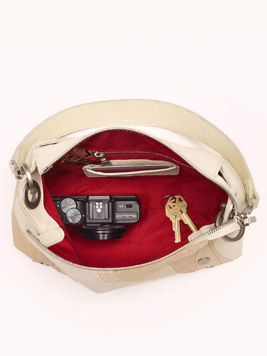 This Hammitt Los Angeles Bryant Medium Crossbody Bag in Coastal Cream, part of the Coastal Cream collection, offers a versatile crossbody and shoulder bag design. Its open cream exterior reveals a striking red interior with space for essentials such as a camera, keys, and small wallet.