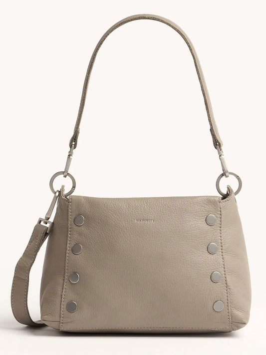 The Hammitt Los Angeles Bryant Medium Crossbody Bag in Pewter Pebble features pebbled leather, silver rivet accents, a short shoulder strap, and adjustable crossbody straps, shown against a plain background.