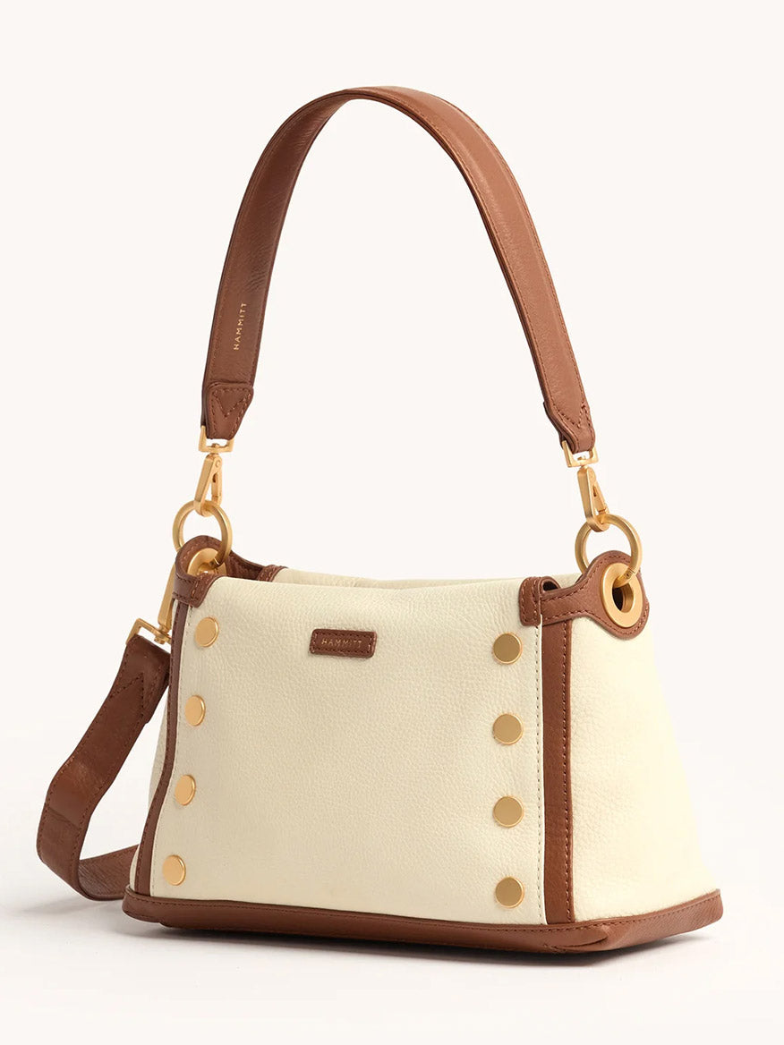The Hammitt Los Angeles Bryant Medium Crossbody Bag in Courtyard Cream features a cream body, brown pebbled leather trim, gold-tone hardware, stud accents, and two detachable straps.