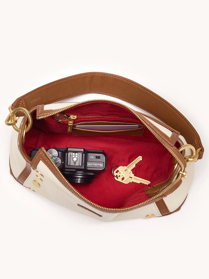 The Hammitt Los Angeles Bryant Medium Crossbody Bag in Courtyard Cream features pebbled leather with a red interior, and can hold a compact camera plus two keys.