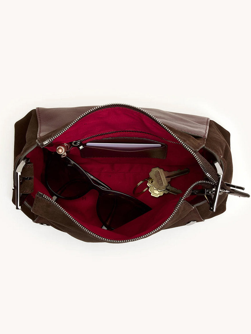 Open Hammitt Los Angeles Bryant Medium Crossbody Bag in Belted Suede/Gunmetal with red interior, revealing sunglasses, a pen, and keys inside.