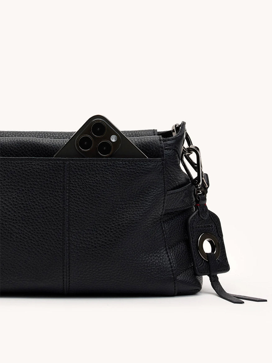The Hammitt Los Angeles Bryant Medium Crossbody Bag in Moto Black/Gunmetal features sleek leather, a handy keychain, and an outer pocket with a smartphone partially visible.