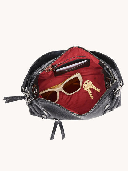 An open Hammitt Los Angeles Bryant Medium Crossbody Bag in Moto Black/Gunmetal with a red interior, holding cream sunglasses, a set of keys, and a smartphone.