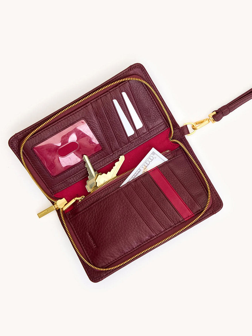The Hammitt Los Angeles Bryant Wallet in Cherrywood Pebble/Brushed Gold is open, revealing card slots, a photo holder, keys, cash, and a red pen inside.