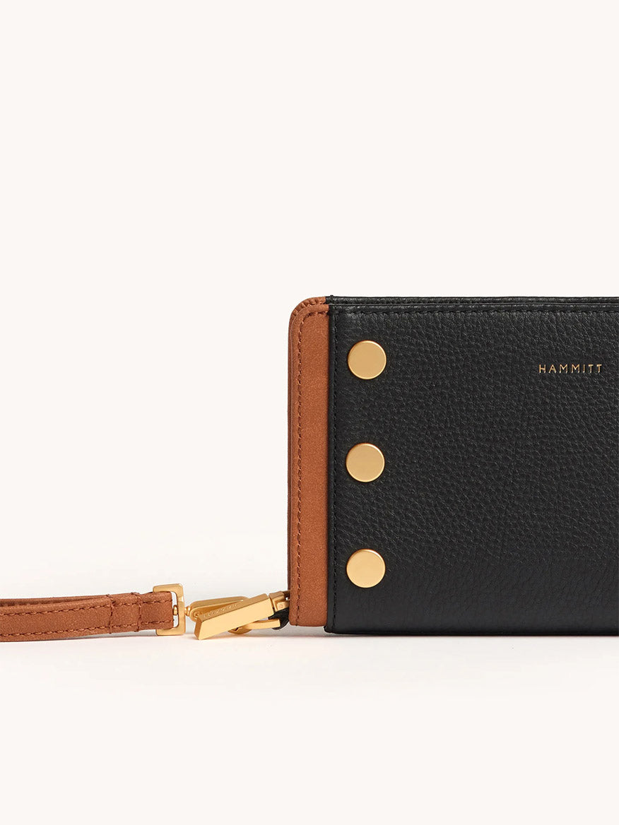 The Hammitt Los Angeles Bryant Wallet in North End features a sleek continental design with black leather, brown trim, gold hardware with three studs, a detachable brown wrist strap, and "HAMMITT" in gold text.
