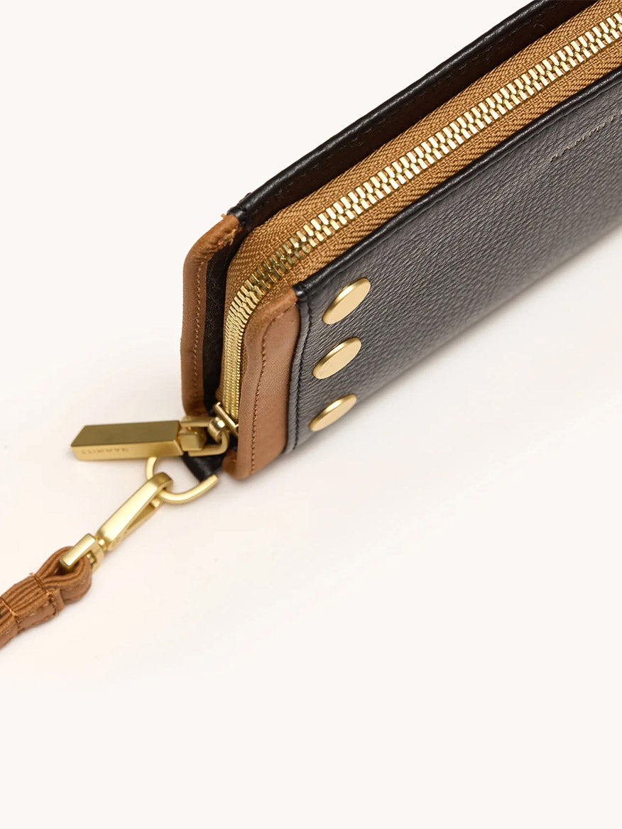 Close-up of the Hammitt Los Angeles Bryant Wallet in North End, showcasing a sleek continental design with brown leather, a gold zipper, three gold studs, and a detachable wrist strap.